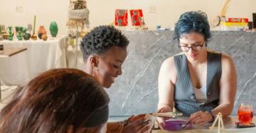Three women painting and crafting at a table.